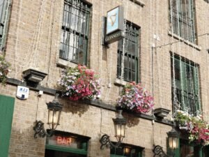 Exterior of one of the best Dublin pubs, adorned with hanging flower baskets and festive lights, featuring a traditional Guinness sign and inviting ambiance.