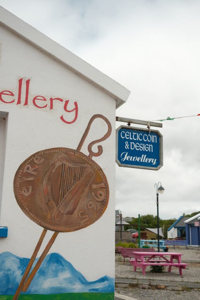 Shop sign for Celtic Coin & Design Jewellery in Ireland, featuring a mural of an Irish harp coin, offering Celtic-inspired jewelry and souvenirs.