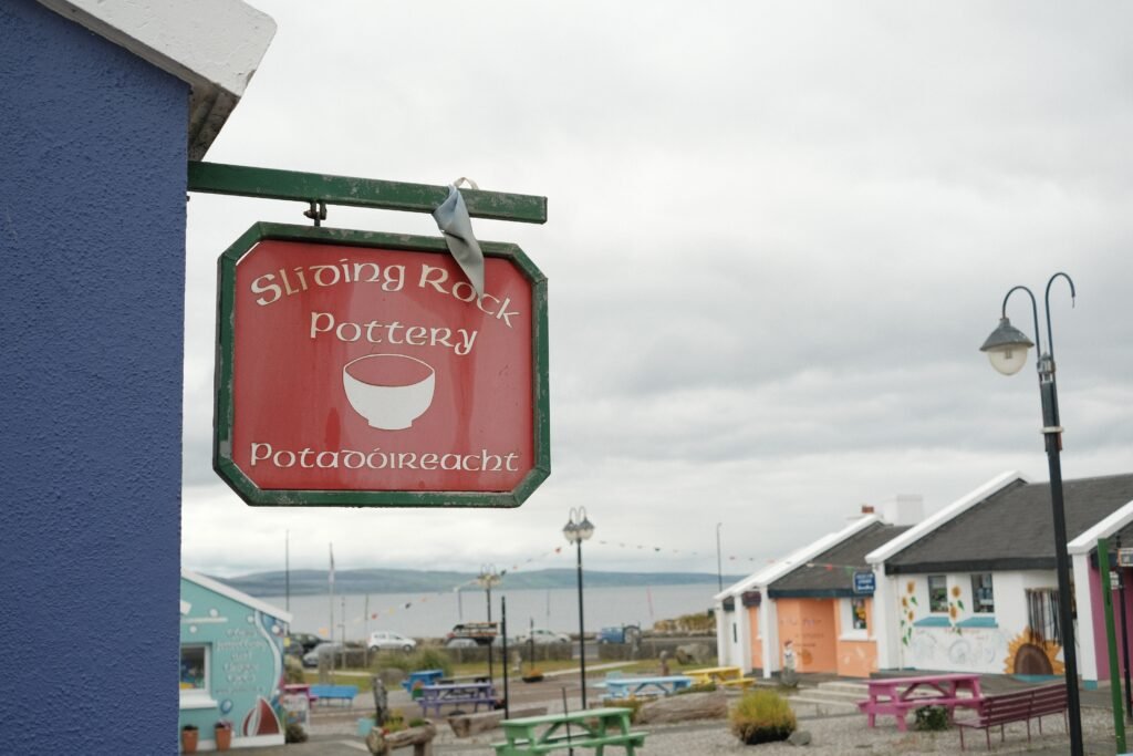 Sign for Sliding Rock Pottery at an Irish craft village, offering handmade pottery and locally crafted gifts, with views of the surrounding coastline.