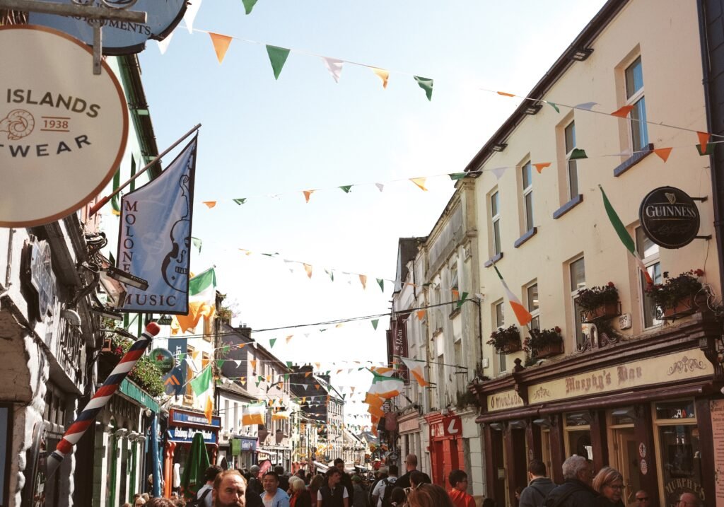 usy Quay Street in Galway City with colorful flags and vibrant storefronts, showcasing the lively atmosphere of one of Galway’s most popular areas for visitors.