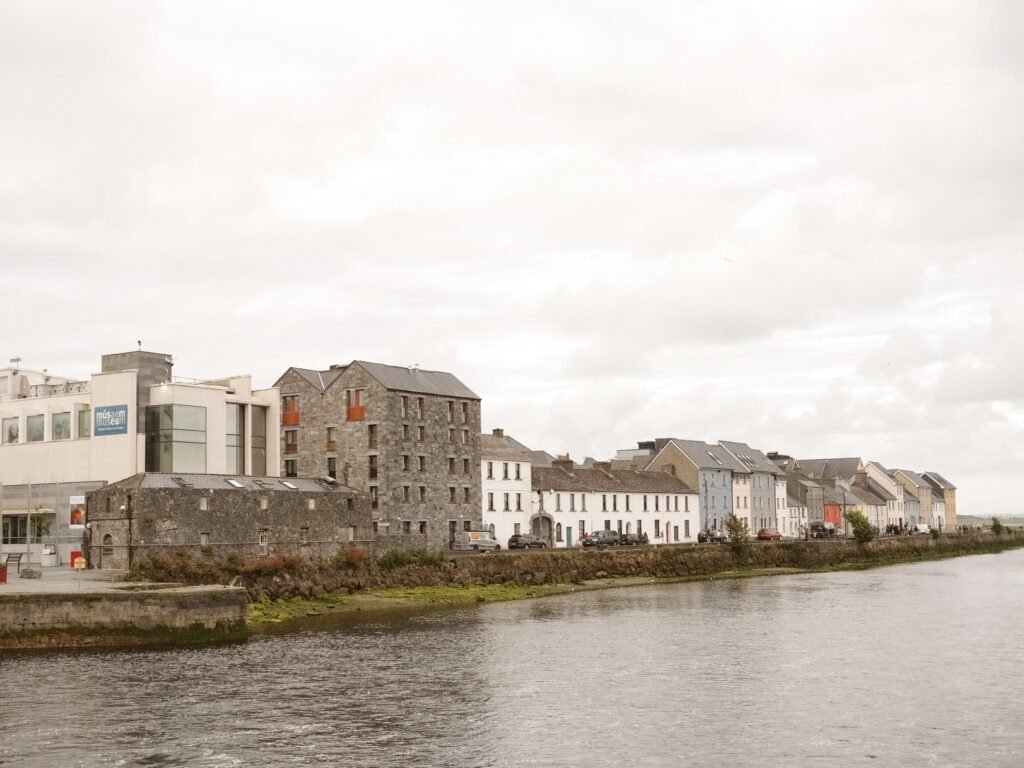 View of colorful buildings along the water in Galway City, showcasing one of the popular areas to stay. This location highlights the charm of Galway's best lodging options, including hotels and accommodations along the waterfront.