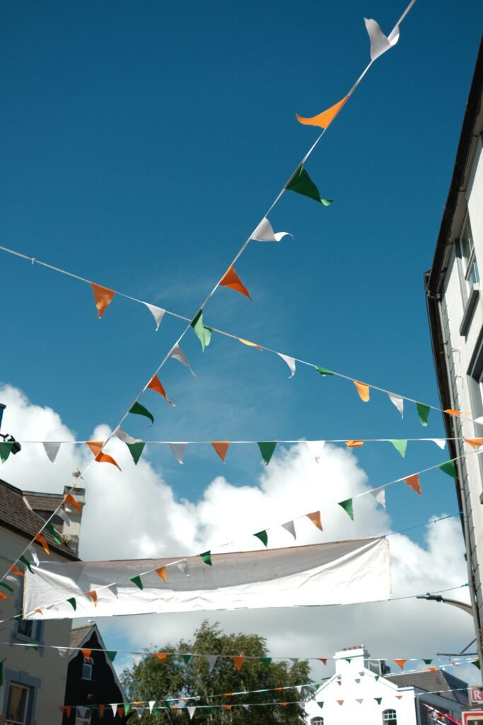 Bright, colorful bunting flags against a clear blue sky in Galway City, Ireland. This festive display highlights the vibrant and welcoming atmosphere of Galway, one of the best cities to stay in during your visit to Ireland.