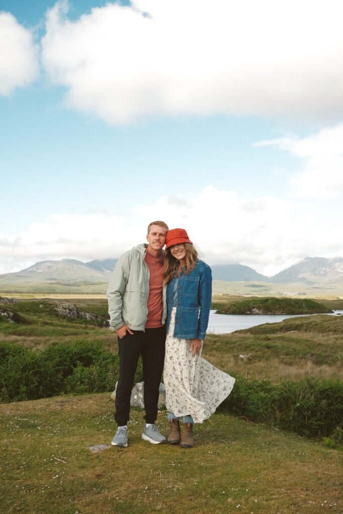 Couple dressed in light jackets and boots, standing in the Irish countryside during summer. Perfect for showcasing what to wear while exploring Ireland’s rural landscapes, with practical and stylish clothing for mild and unpredictable weather. Includes layering tips for a comfortable and scenic outdoor adventure.