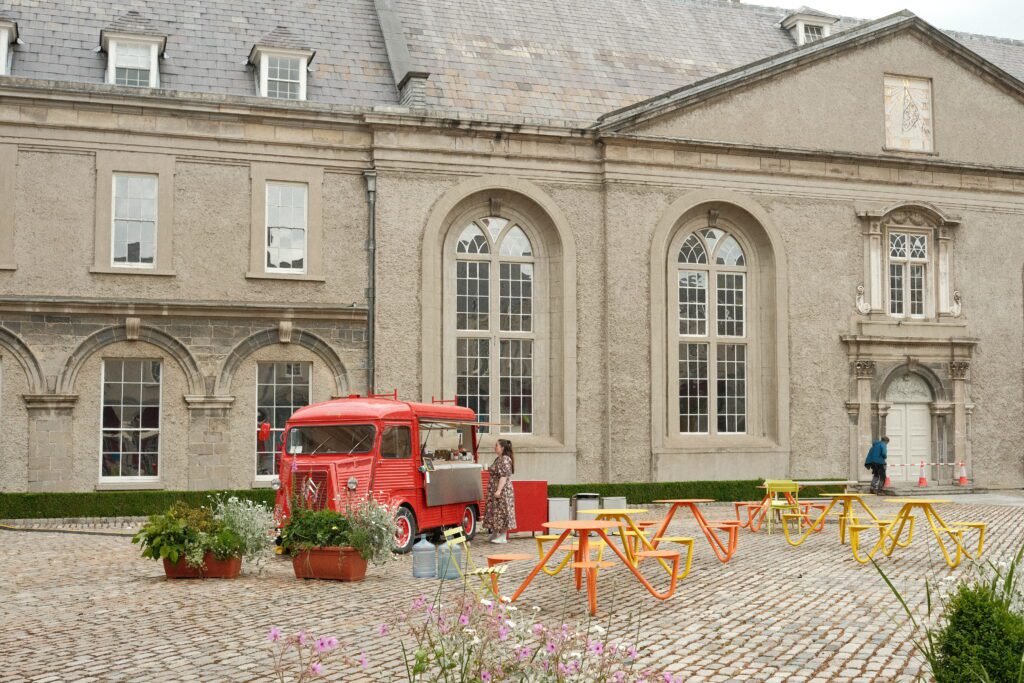 A charming courtyard at the Irish Museum of Modern Art (IMMA) in Dublin, featuring a red vintage food truck and colorful outdoor seating.