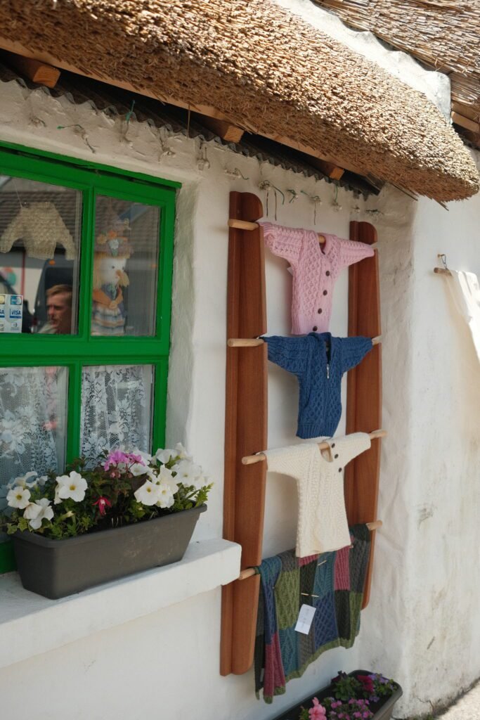 Display of handmade Irish wool sweaters outside a traditional shop, featuring Aran knit designs, a popular souvenir and gift from Ireland.