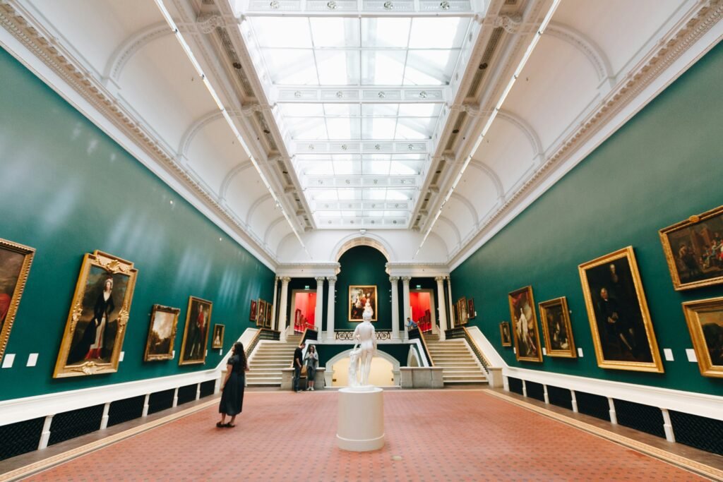 Visitors admiring paintings and sculptures inside the National Gallery of Ireland in Dublin, with a large skylight and elegant interior design.