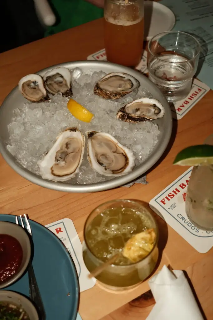 A plate of fresh oysters on ice served with lemon and dipping sauces at Fish Bar in St. Thomas during a bachelorette dinner.