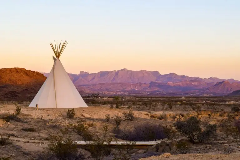 A tipi in Terlingua, Texas, with desert landscape and mountains in the background at sunset near Big Bend National Park.