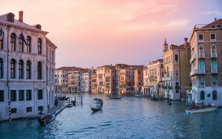 Gondolas on Venice's Grand Canal with historic buildings at sunset, capturing the beauty of the city.