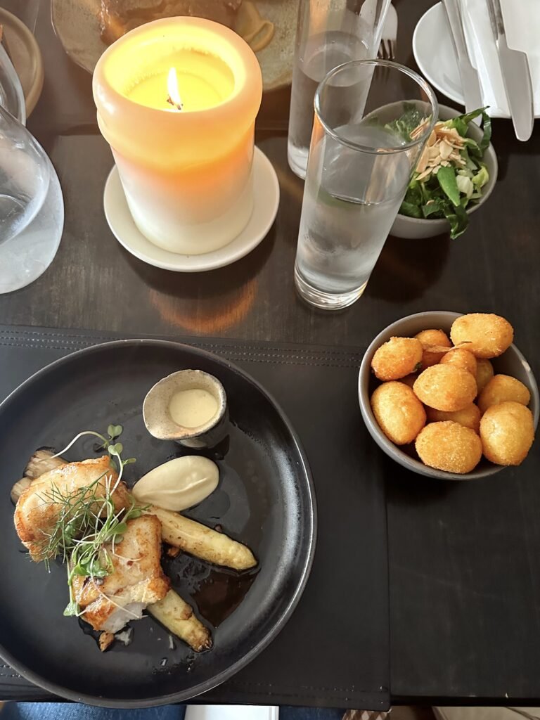 A gourmet dish served at Mulcahy's Bar & Restaurant in Kenmare, Ireland, featuring roasted chicken, asparagus, and crispy potato bites, with a cozy candle-lit table setting.