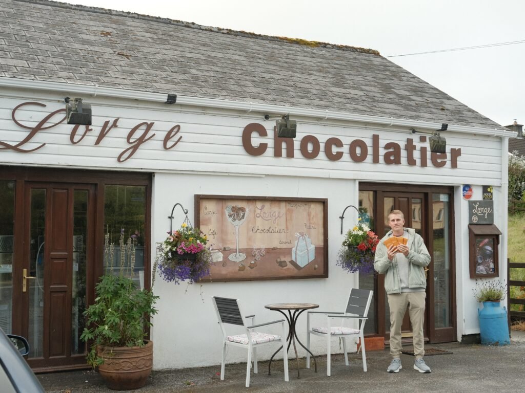 Lorge Chocolatier, Kenmare, Ireland – A visitor holding chocolates outside Lorge Chocolatier, a popular local shop in Kenmare known for its handcrafted sweets and chocolate-making classes. A must-visit spot for anyone shopping in Kenmare, County Kerry.