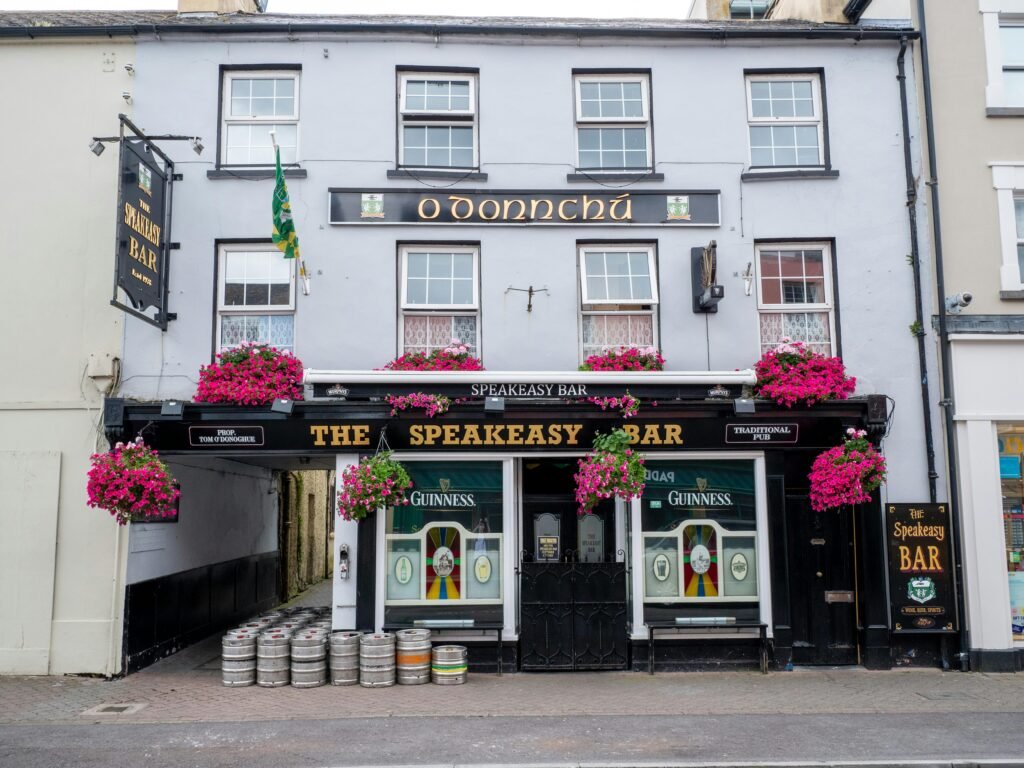 Traditional Irish pub in Killarney, Ireland, featuring a cozy exterior with colorful signage and flower-adorned windows. Known for its lively atmosphere, this pub offers visitors a chance to enjoy live Irish music, local beers, and classic dishes in the heart of County Kerry.